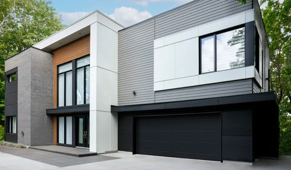 Maison moderne, formes carrées, jouant les volumes et les textures, porte de garage double Vog Noir